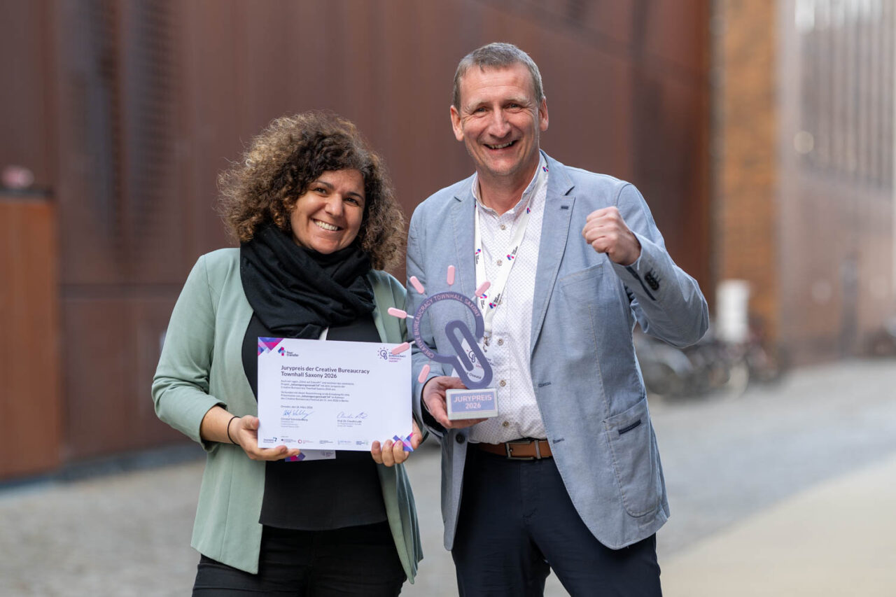 Das Bild zeigt André Oswald, Bürgermeister von Johanngeorgenstadt sowie seine Kollegin Jana Busch. Mit ihrem Projekt "Johanngeorgenstadt54" sind sie die Gewinner des Jurypreises der Creative Bureaucracy Townhall saxony 2026.